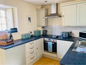 una cucina con armadi bianchi e piano di lavoro blu di Driftwood Cottage pets go free WiFi included a Hunstanton
