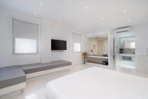 a white bedroom with a bed and a tv at Cycladic Suites in Fira