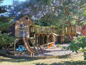 ein Baumhaus mit Rutsche und Spielplatz in der Unterkunft Gîte Le Petit Bacchus in Sainte-Croix-Hague
