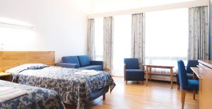 une chambre d'hôtel avec 2 lits et des chaises bleues dans l'établissement Pajulahti Olympic & Paralympic Training Center, à Nastola