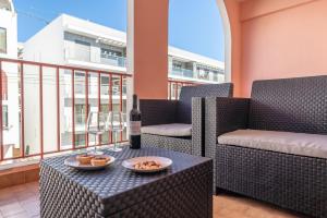 a bottle of wine sitting on a table on a balcony at Quarteira Beach - 2 D by HelloVacations in Loulé