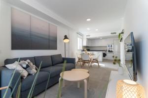 Una sala de estar con un sofá azul y una mesa. en Cala Luxo en Cala de Mijas a metros del mar, en Mijas Costa