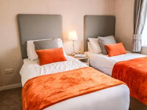 2 camas con almohadas de color naranja en una habitación en Rashierigg en Richmond