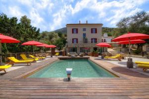 a pool with chairs and umbrellas and a building at Hôtel Casale Olmia 