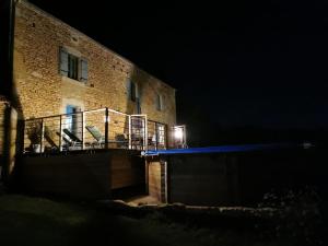 a building with a balcony with chairs on it at night at Maison typique périgourdine avec piscine in Paulin