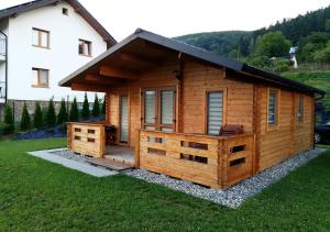 a log cabin with a deck in front of a house at Domki Na Stoku Laworty in Ustrzyki Dolne