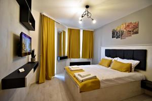 a bedroom with a large bed with yellow curtains at Apartment Orpheus in Velingrad