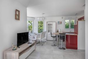 Una cocina y una sala de estar con TV de pantalla plana. en Maison 6 personnes avec accès privé à la plage !, en Penvins