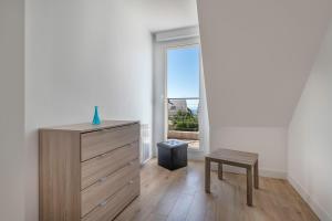Un dormitorio con una cómoda, un taburete y una ventana. en Maison 6 personnes avec accès privé à la plage !, en Penvins