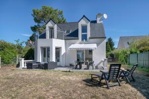 Una casa con dos sillas y una mesa en el patio. en Maison 6 personnes avec accès privé à la plage !, en Penvins