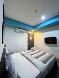 a bedroom with a large bed with a tv on the wall at Metroinn Hotel in Arau
