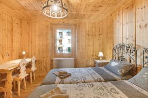 a bedroom with two beds and a wooden wall at Casa Cecilia tra Bormio e Livigno in Valdidentro