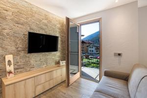 ein Wohnzimmer mit einem TV an einer Steinmauer in der Unterkunft Casa Cecilia tra Bormio e Livigno in Valdidentro