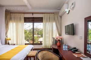 a hotel room with a bed and a desk and a window at Entebbe Traveller's Hotel in Entebbe