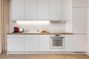 a white kitchen with white cabinets and a sink at Happy Stay Chlebova Residence in Gdańsk