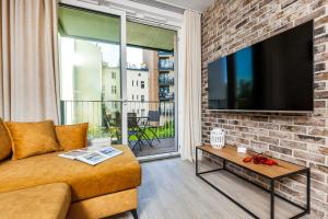a living room with a brick wall and a flat screen tv at Happy Stay Chlebova Residence in Gdańsk