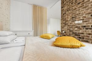 a bedroom with a bed with yellow pillows and a brick wall at Happy Stay Chlebova Residence in Gdańsk