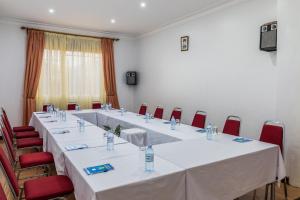une salle de réunion avec de longues tables et des chaises rouges dans l'établissement Entebbe Traveller's Hotel, à Entebbe