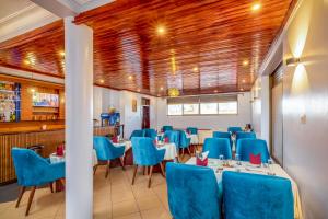 a dining room with blue chairs and tables at Entebbe Traveller's Hotel in Entebbe