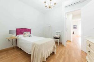 Habitación blanca con cama y lámpara de araña. en Casa Angeline Azul 1 By KubiK, en Cáceres
