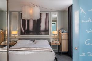 a bedroom with a bed and two tables and a mirror at Hotel Litteraire Le Swann, BW Premier Collection in Paris