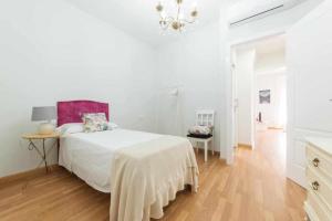 een witte slaapkamer met een bed en een kroonluchter bij Casa Angeline Rosa 2 By KubiK in Cáceres