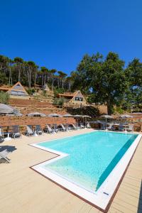 una grande piscina con sedie e ombrelloni di Il Castagno Toscana Glamping a Campiglia Marittima