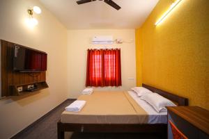 a small room with a bed and a television at VR Inn , 900 Meters from Rock Beach in Pondicherry