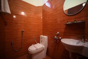 a bathroom with a toilet and a sink and a mirror at VR Inn Comfort stay in Pondicherry in Puducherry