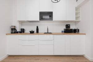 a kitchen with white cabinets and a microwave at Seaside Apartment Wybrzeze Dziwnow in Dziwnów