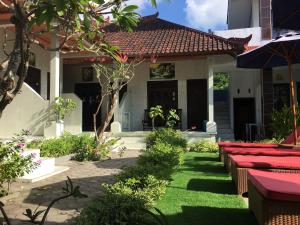 a garden with red benches in front of a house at Wahyu Homestay 1 in Nusa Lembongan