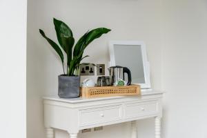 a white table with a mirror and a plant on it at The Retreat New Forest, Hinton in Christchurch