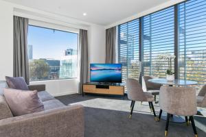 uma sala de estar com uma televisão e uma mesa e cadeiras em Christchurch City Hotel em Christchurch
