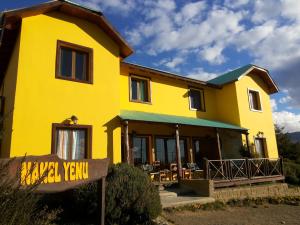 a yellow house with a sign in front of it at Hostel Nakel Yenu in El Calafate