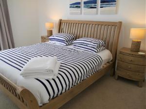 a bed with blue and white striped sheets and pillows at Driftwood in Kippford