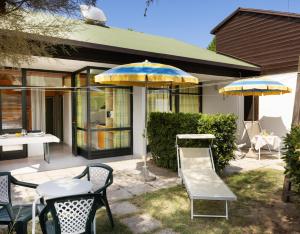 a patio with tables and chairs and umbrellas at Residence Mare Pineta in Casal Borsetti