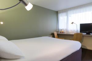 a bedroom with a bed and a desk and a window at Kyriad Annecy Nord - Epagny in Metz-Tessy