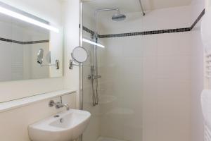 bagno bianco con lavandino e doccia di Kyriad Annecy Nord - Epagny a Metz-Tessy
