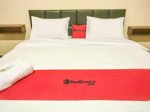 Una cama blanca con un punto rojo. en RedDoorz @ Jalan Gelanggang Remaja Waena Jayapura, en Sentani