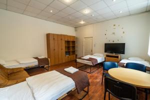 a room with three beds and a table and a tv at Apartamentai Klaipeda Inn in Klaipėda