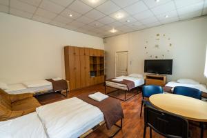 a room with three beds and a table and a tv at Klaipeda INN Private Parking and Kitchen in Klaipėda