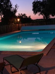 una piscina por la noche con mesa y sillas en Gites le Mathelin, en Lamothe-Montravel