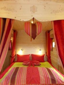 um quarto com uma cama grande e almofadas vermelhas em La Roulotte de Bourgogne em Brianny