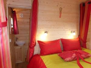 um quarto com uma cama com almofadas vermelhas e um lavatório em La Roulotte de Bourgogne em Brianny