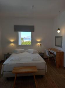 a bedroom with a bed with a window and a desk at Maria Elena - Suite Home in Mýkonos City