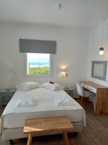 a bedroom with a bed and a desk and a window at Maria Elena - Suite Home in Mýkonos City