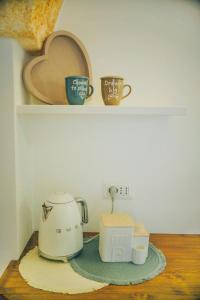 una macchinetta del caffè e tazze sedute su uno scaffale di Casa Nenetta a Fasano