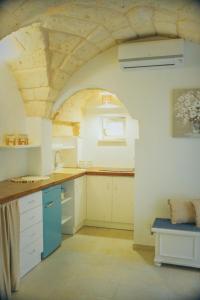 una cucina con armadi bianchi e soffitto in legno di Casa Nenetta a Fasano