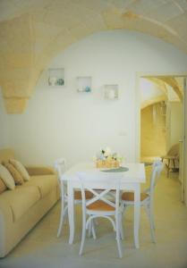 un tavolo bianco con sedie in una stanza con divano di Casa Nenetta a Fasano