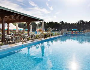 a pool at a resort with tables and chairs at Residence Mare Pineta in Casal Borsetti